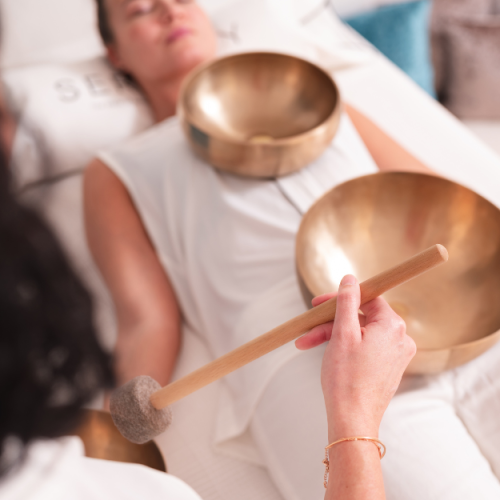 Frau erlebt eine entspannende Klangschalenmassage zur Förderung von Wohlbefinden und innerer Harmonie.